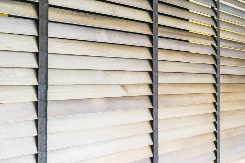 Holzjalousien vor einem Fenster.