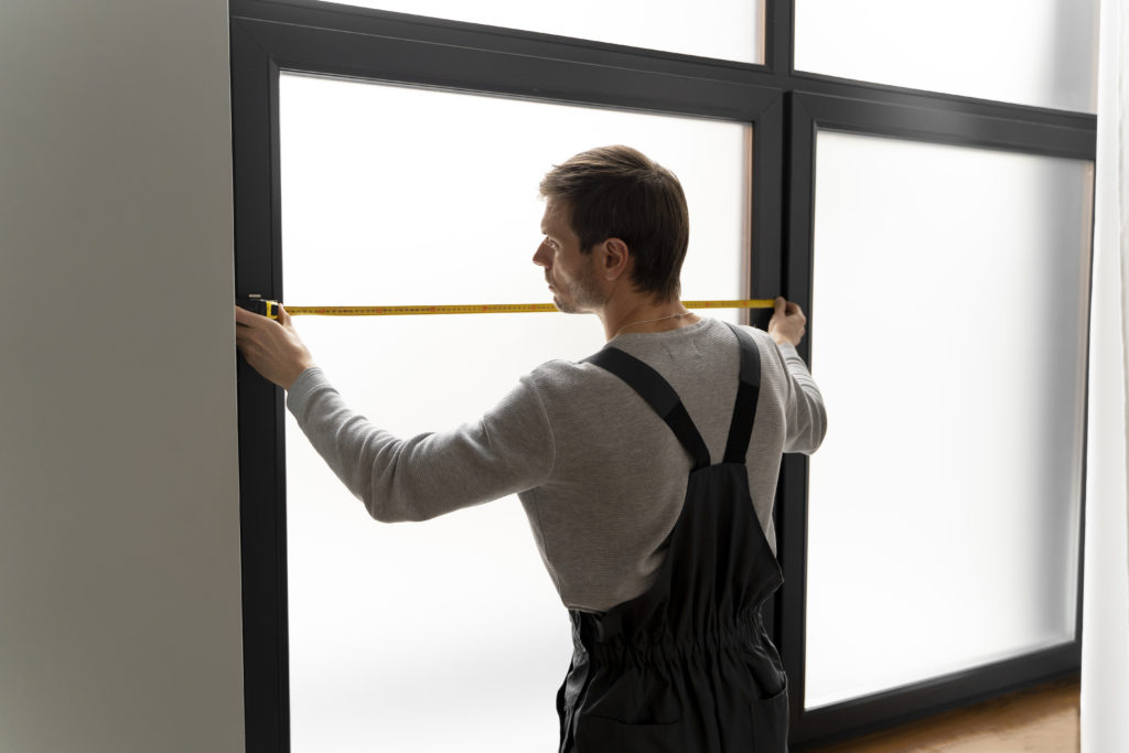 Eine Person in Arbeitskleidung repariert eine defekte Rolllade.